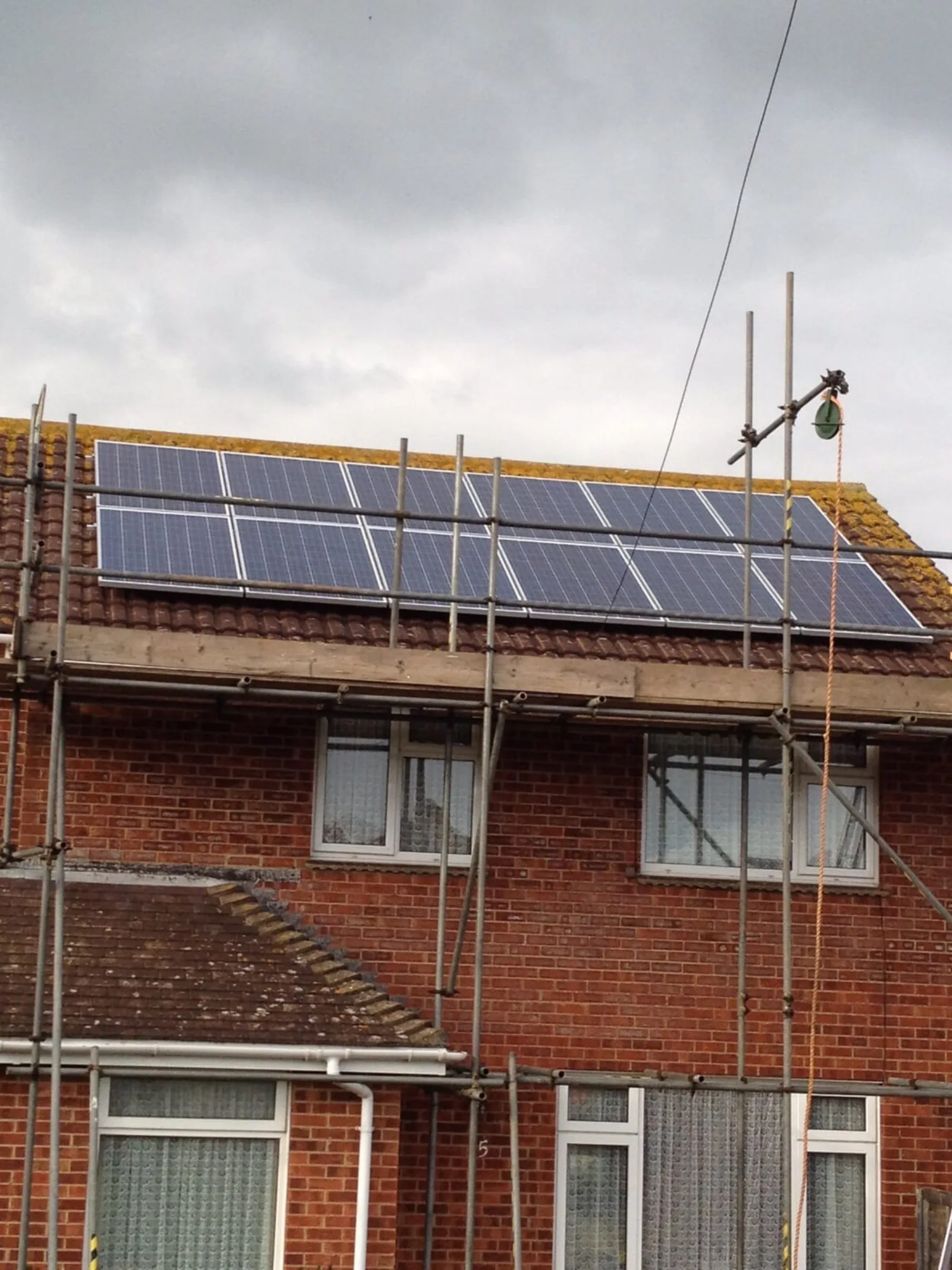 Roofer inspecting tiles around newly installed solar panels on a Hampshire home